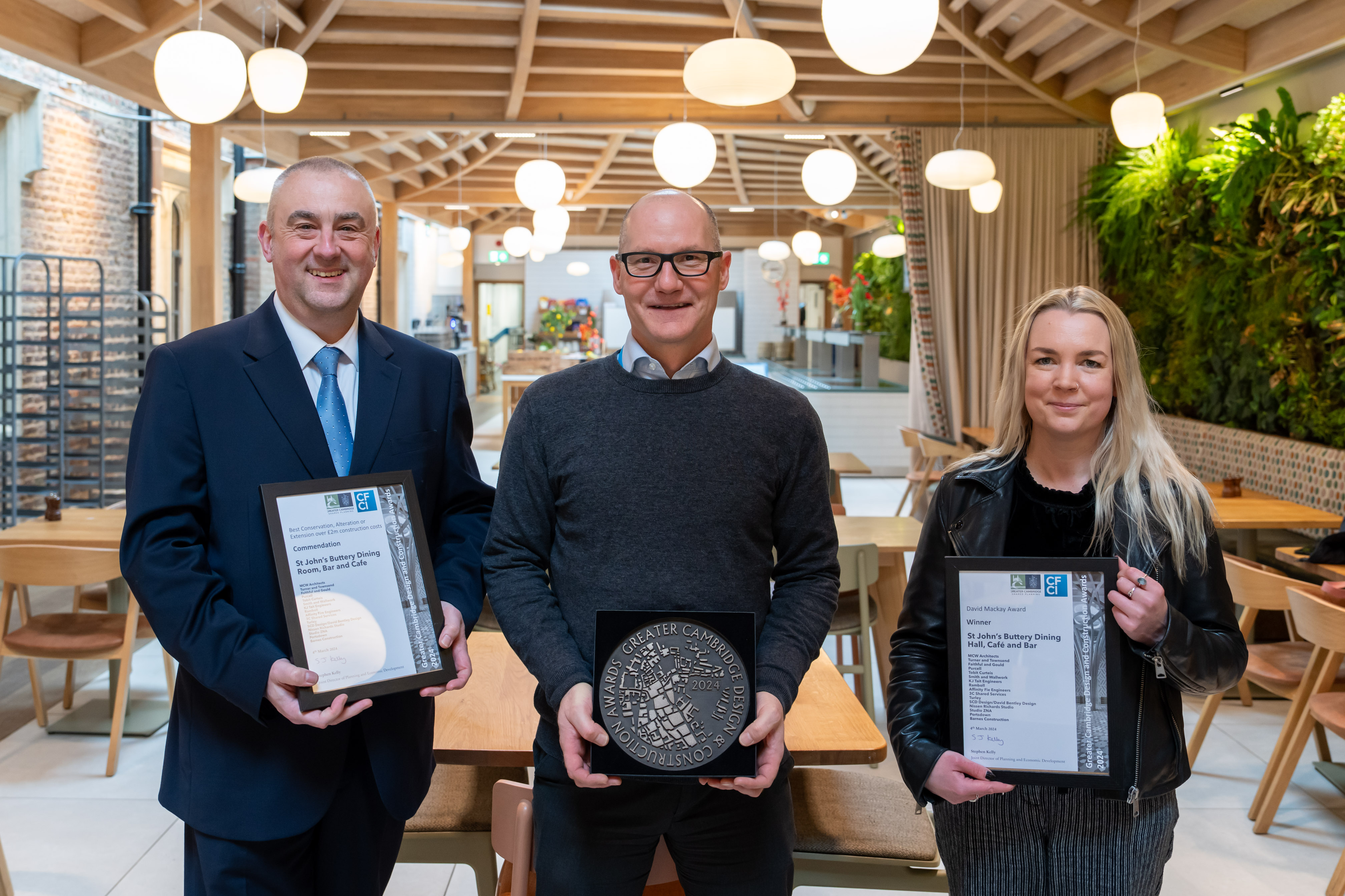 Three members of staff in the new Buttery with the award and certificates