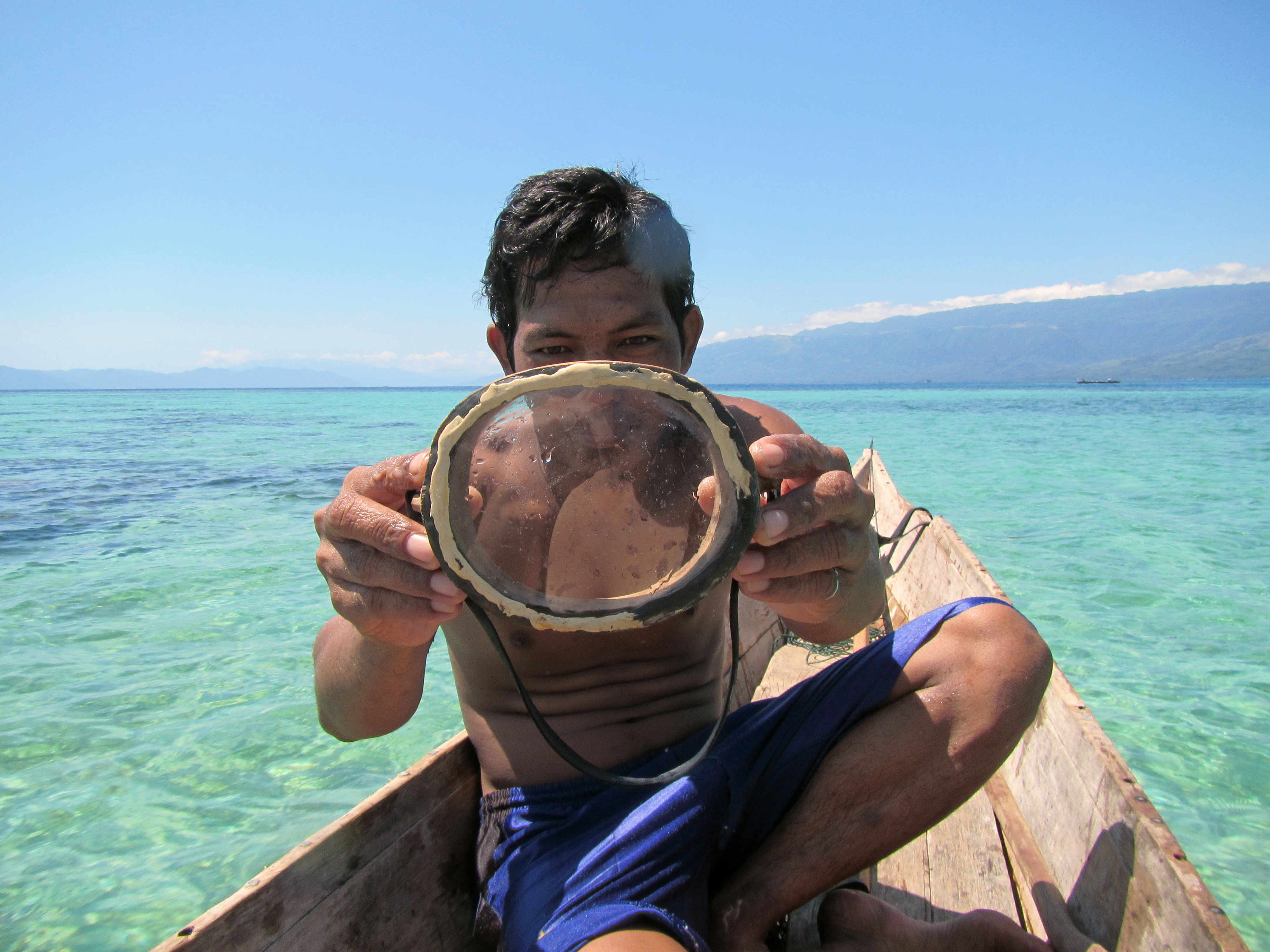 A Bajau diver displays a traditional wooden diving mask.